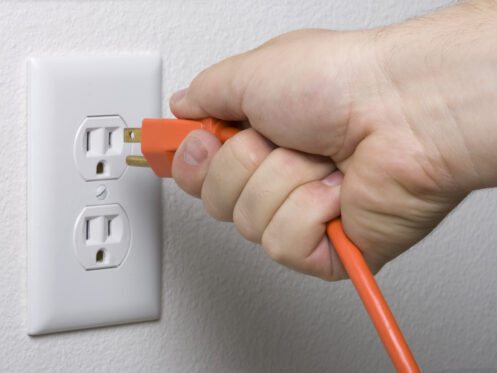 A person plugging in a cord into an outlet
